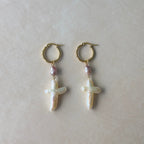 Pair of hoop earrings with cross-shaped pearls on a light background