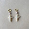 Pair of pearl earrings with gold hooks on a light gray background