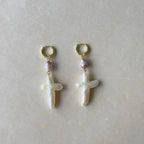 Pair of pearl earrings with gold hooks on a light gray background